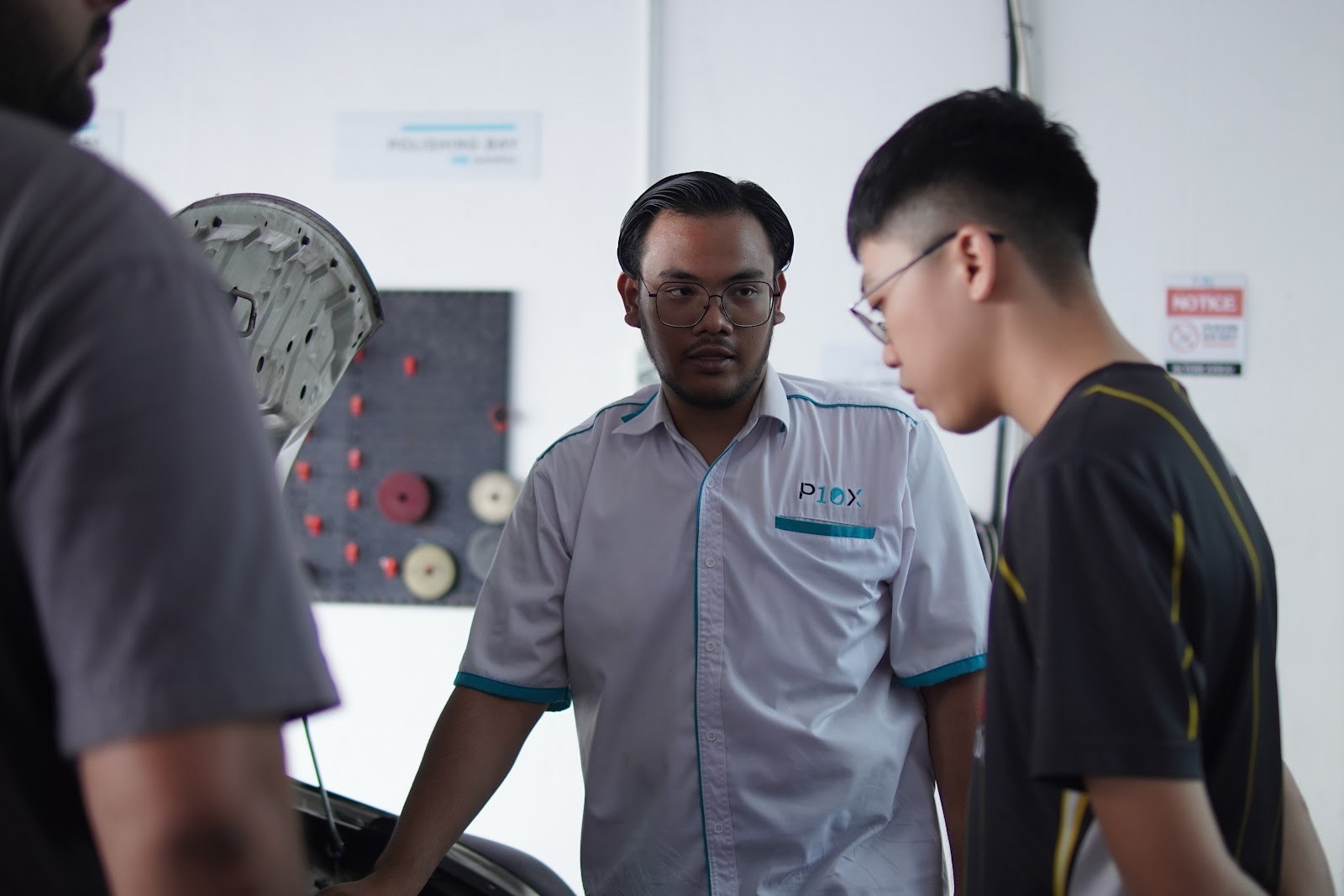 P10X Academy instructor briefing trainees beside open bonnet