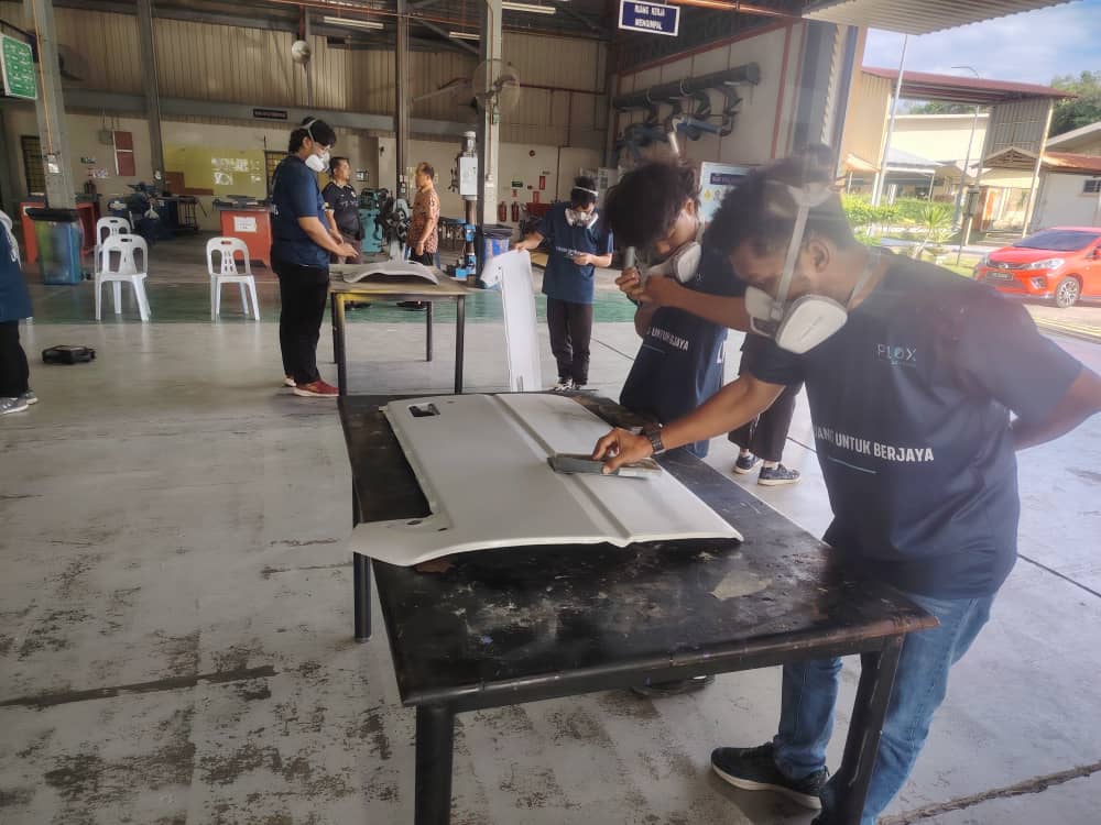 Pelajar mengamplas panel badan kereta secara tangan semasa latihan detailing P10X Academy