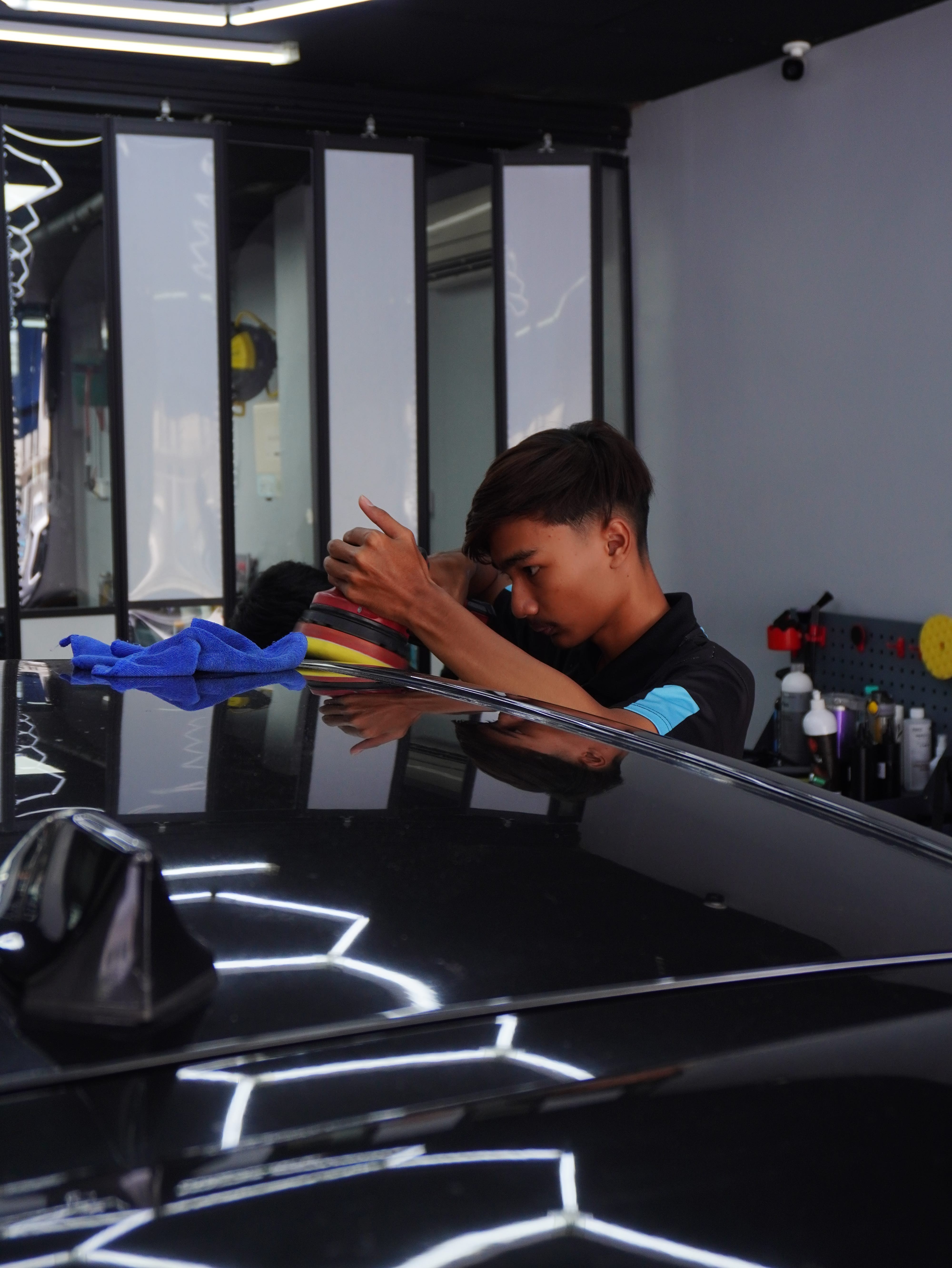 Pelajar TVET P10X Academy menggilap badan kereta dengan mesin polisher semasa sesi bimbingan