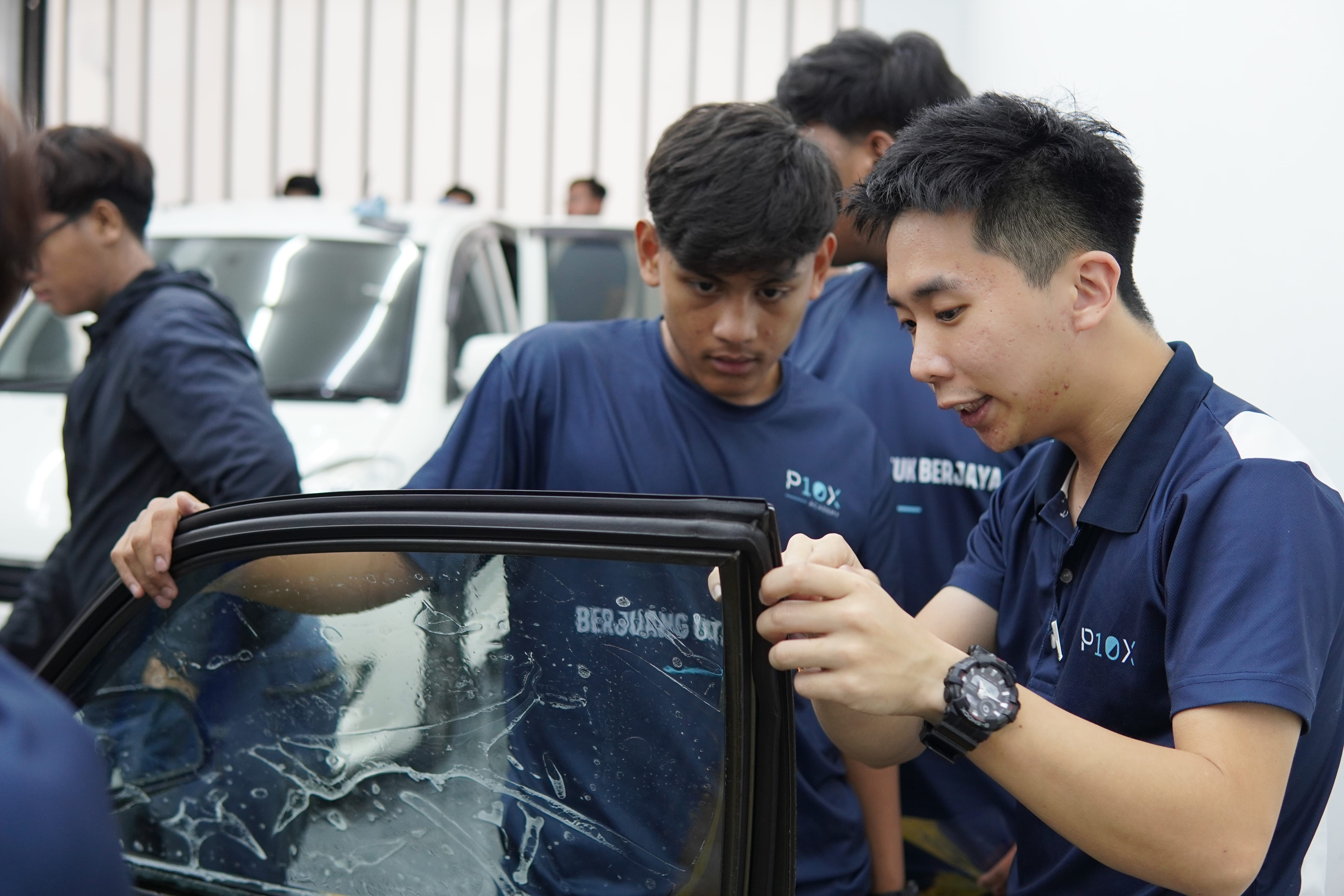 Jurulatih P10X Academy membimbing pelajar semasa pemasangan filem tinted