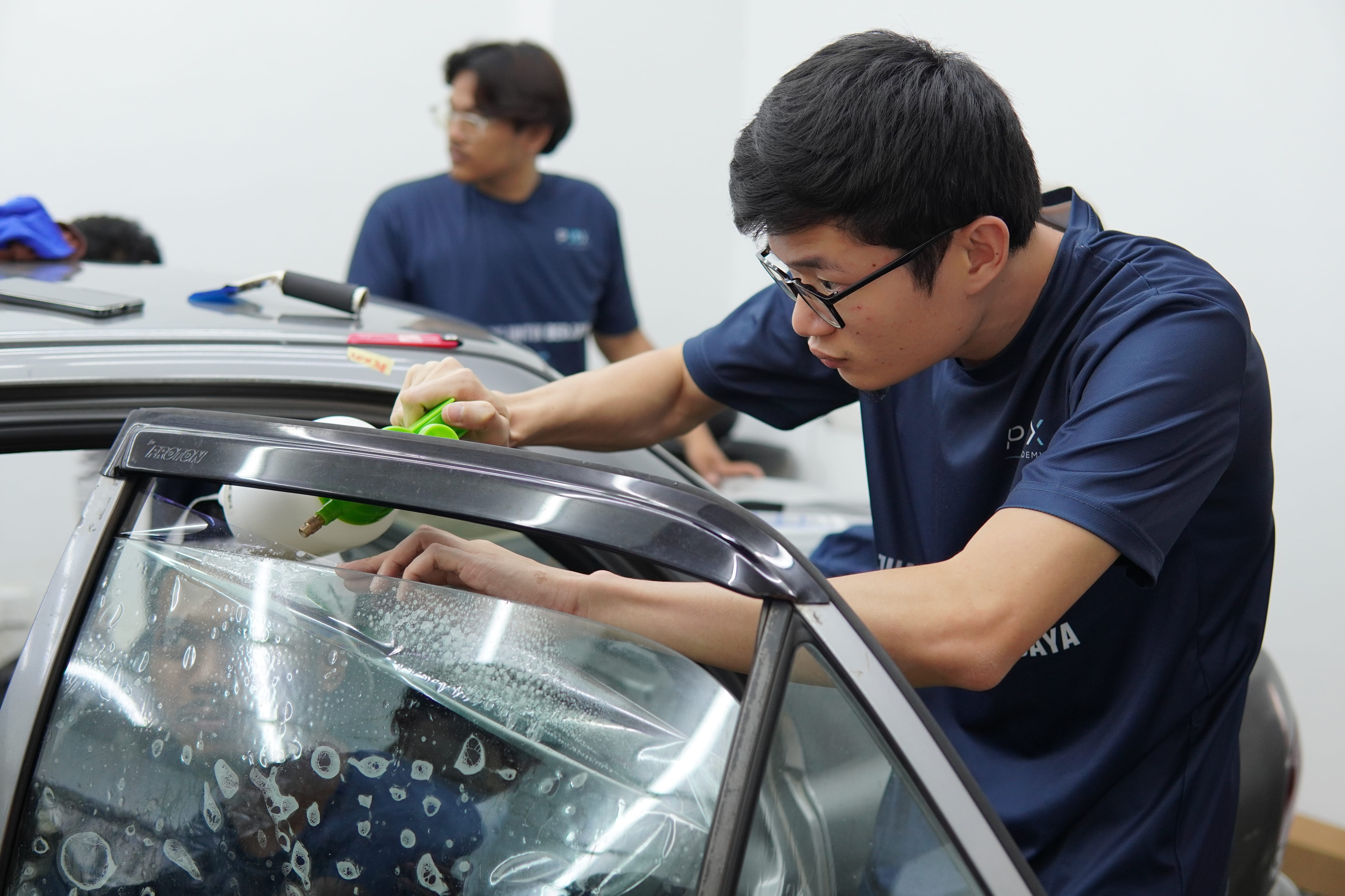 Pelajar berlatih teknik squeegee semasa kursus tinted 5 hari di P10X Academy